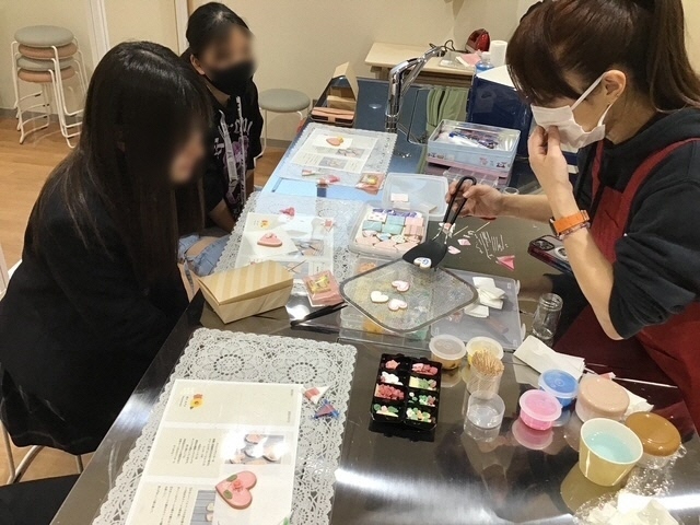 講師からクッキーへの装飾の仕方を教わる参加者